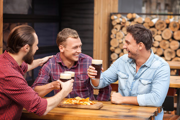 Fototapeta premium Attractive guys are enjoying alcohol drink in pub