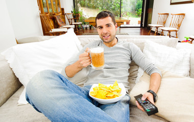 Hispanic pleased male wearing light blye sweater enjoying potato