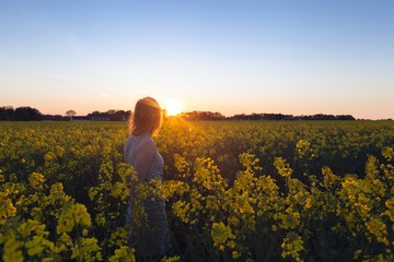 Beautiful woman walking in flower field at sunset