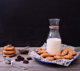 Bottle of milk with cookies and some ingredients on rustic table