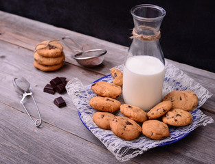 Bottle of milk with cookies and some ingredients on rustic table
