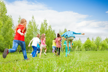 View from behind of kids running through  field