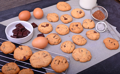 Home baked chocolate cookies on baking paper with ingredients on
