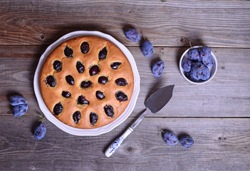 Homemade plum pie on wooden background