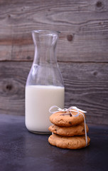 Stack of Chocolate chip cookie and bottle of milk on black backg