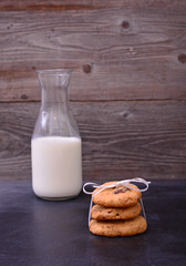 Chocolate cookies with milk on black table. Stacked chocolate chip cookies