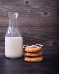 Stack of Chocolate chip cookie and bottle of milk on black backg