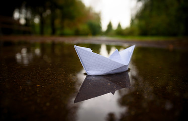 Paper boat floating on water in autumn park