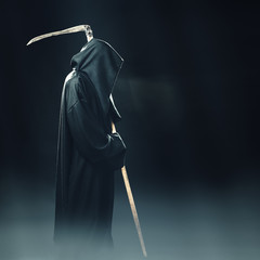 death with scythe standing in fog at night