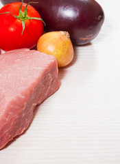 Food background of fresh meat, onion, tomato, pepper, eggplant at the wooden board with copy space