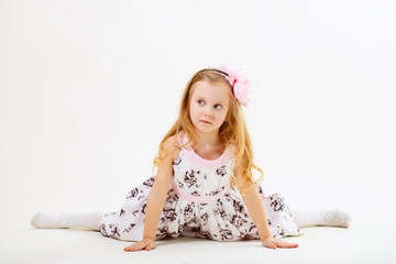Naklejka premium Little blond girl sitting on the twine in front of white backgro