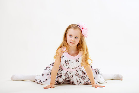 Little blond girl sitting on the twine in front of white backgro