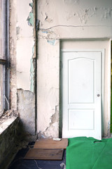 Door in the old abandoned hall. Shabby sloughing wall on the darkness. 