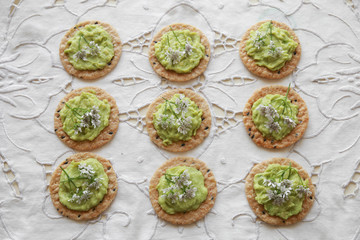 Green avocado crackers with coriander flowers