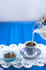 Pouring milk in to a cup of  coffee  in coffee shop vintage color 