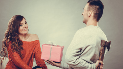 Insincire man holding axe giving gift box to woman