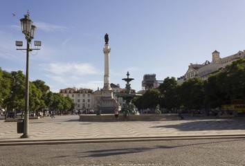 Pedro IV column and fountain in Rossio Square in Lisbon, with people around