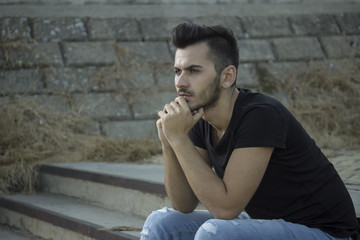 young men posing, sitting on old stairs.