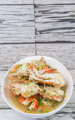Malaysian dish clear crab soup in an oblong plate over wooden background