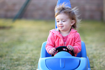 Happy toddler driving a car on the yard