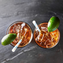 two glasses of iced tea on slate surface with retro straws and limes shot top down overhead