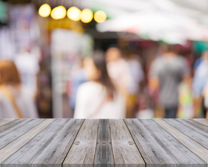 Wooden board empty table in front of people shopping at market fair background. Perspective wood and blur market - can be used for display or montage your products - vintage effect style pictures.