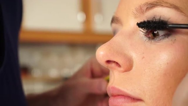 Makeup artist applying black mascara to model eye 4K