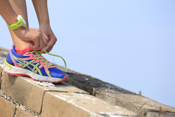 woman runner tying shoelace on china great wall .