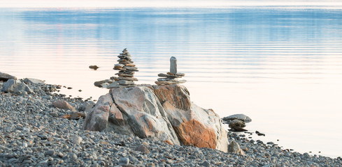 Obraz premium Two sculptures of balancing rocks on a lake shore