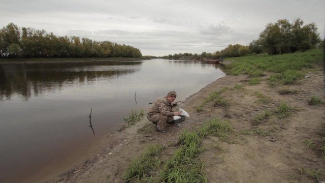 Fisherman changes trolling spinning and throws it into the river