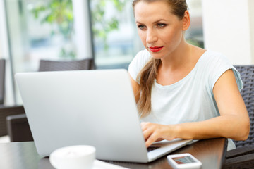 Young business woman sitting in a cafe with a laptop and coffee