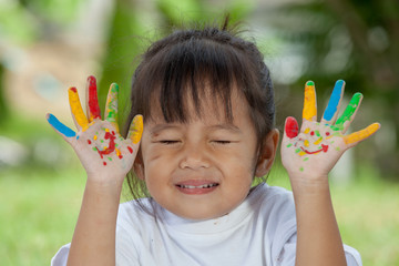 Cute little girl with hands painted on green background