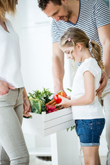 Junge Familie mit Gemüsekiste in der Küche