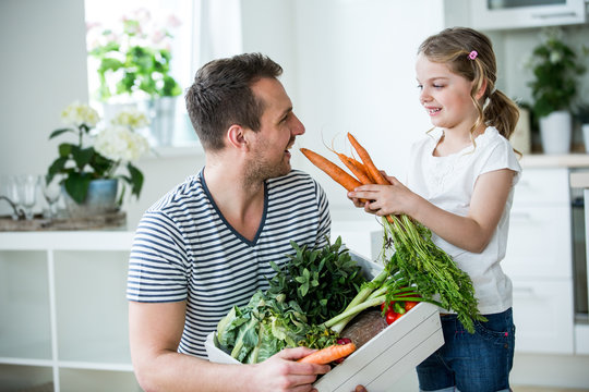 Vater und Tochter mit Gem&uuml;sekiste in der K&uuml;che
