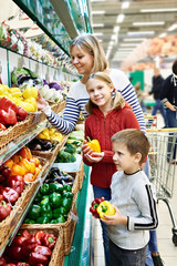 Mother and children with bell pepper in supermarket