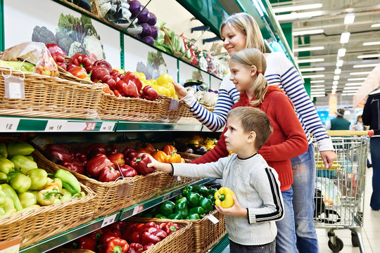 Mother and children with bell pepper in supermarket
