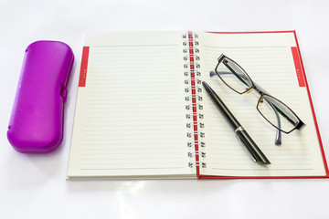 Pen and eyeglasses on a notebook.