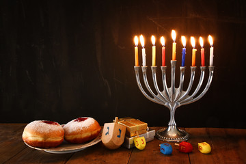 image of jewish holiday Hanukkah with menorah (traditional Candelabra), donuts and wooden dreidels (spinning top). retro filtered image
