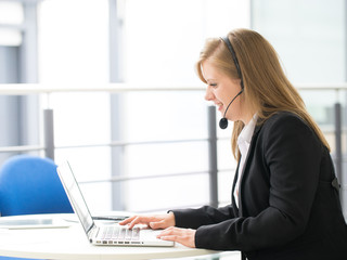 Business woman talking using her headset in the office