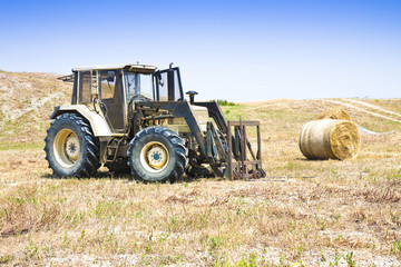 Fototapeta na wymiar Old tractor stopped in a hill with round bales on background (Italy)
