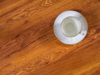 Top view on the cup with saucer, standing on the wooden table
