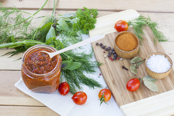 Homemade tomato sauce in glass jar with fresh tomatos, garlic, onion, herbs and spices 