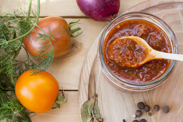 Homemade tomato sauce in glass jar with fresh tomatos, garlic, onion, herbs and spices 