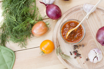 Homemade tomato sauce in glass jar with fresh tomatos, garlic, onion, herbs and spices 