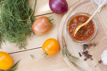 Homemade tomato sauce in glass jar with fresh tomatos, garlic, onion, herbs and spices 