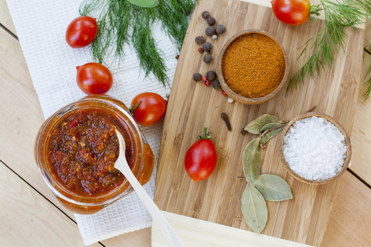 Homemade tomato sauce in glass jar with fresh tomatos, garlic, onion, herbs and spices 