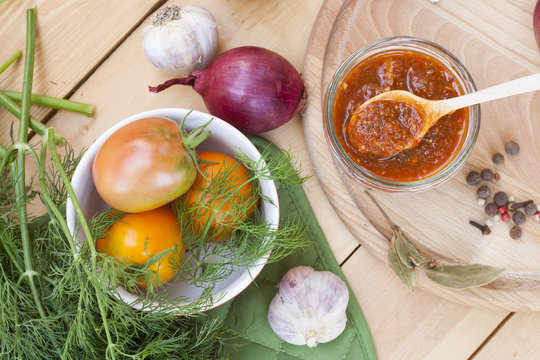 Homemade tomato sauce in glass jar with fresh tomatos, garlic, onion, herbs and spices 