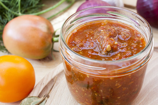 Homemade tomato sauce in glass jar with fresh tomatos, garlic, onion, herbs and spices 