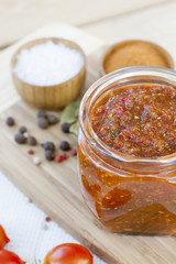 Homemade tomato sauce in glass jar with fresh tomatos, garlic, onion, herbs and spices