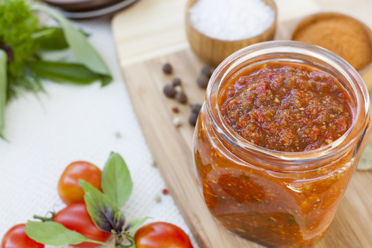 Homemade tomato sauce in glass jar with fresh tomatos, garlic, onion, herbs and spices